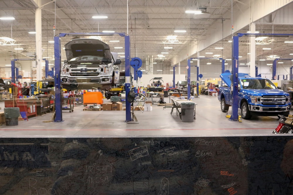 A wide view of a busy repair shop floor with several vehicles raised on lifts
