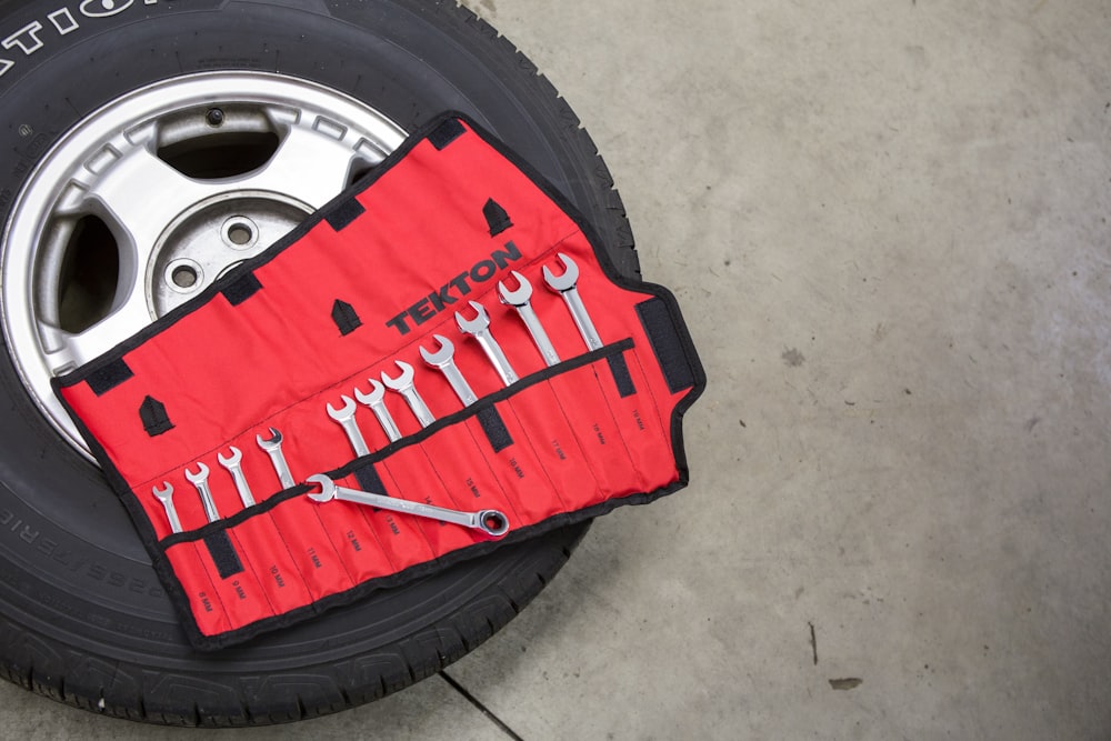 A tire and a roll of wrenches laid out neatly on a shop floor, seen from above