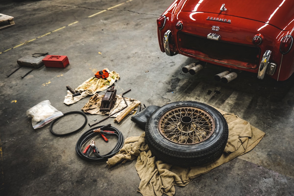 A wire-spoke wheel and hand tools laid out on a shop floor
