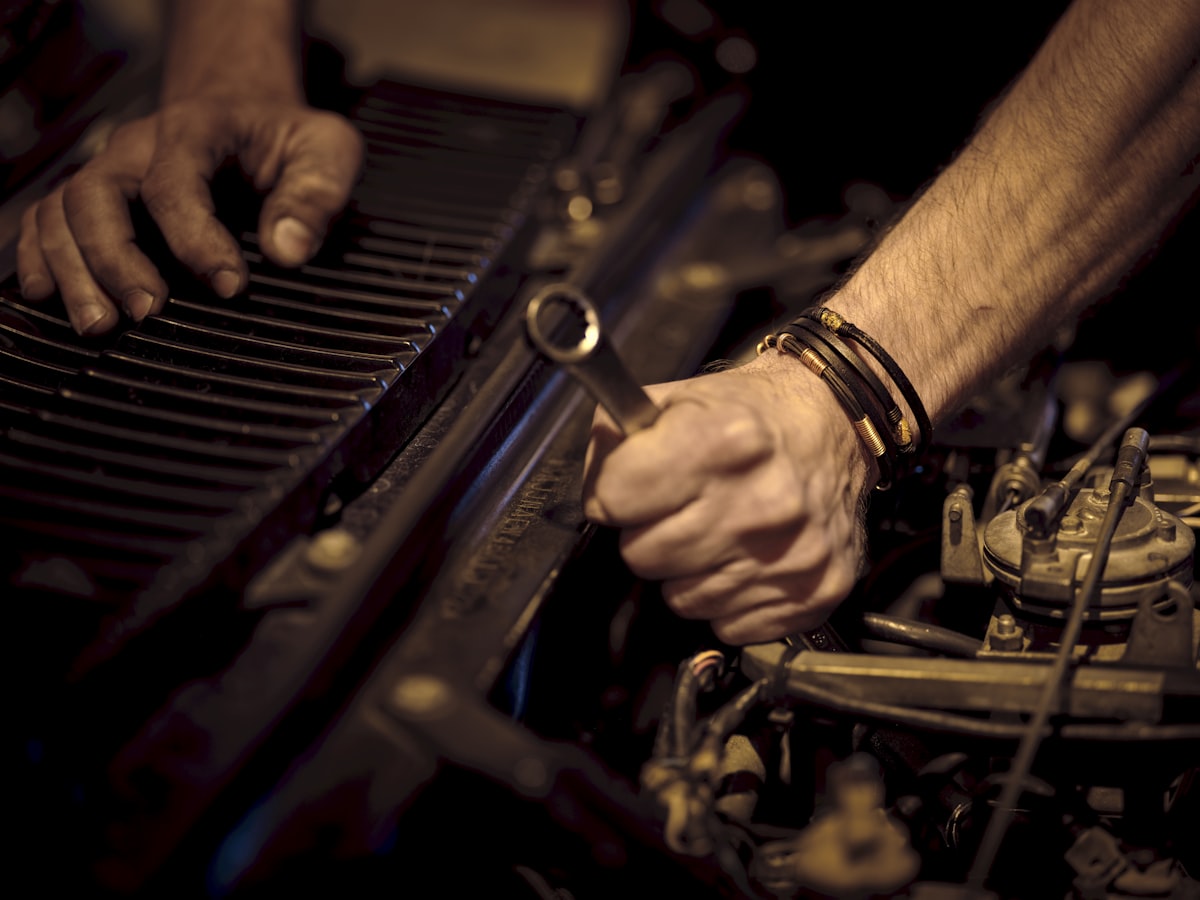 Two hands turning a wrench on an engine component